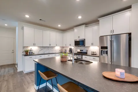 a kitchen with stainless steel appliances granite countertop a sink a stove and a refrigerator with wooden floor