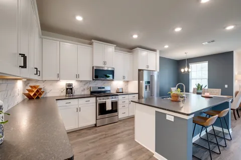 a kitchen with stainless steel appliances granite countertop a stove top oven a sink dishwasher a dining table and chairs with wooden floors