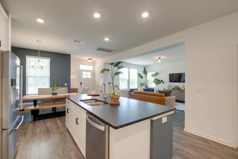 a kitchen with a sink a counter top space and living room view