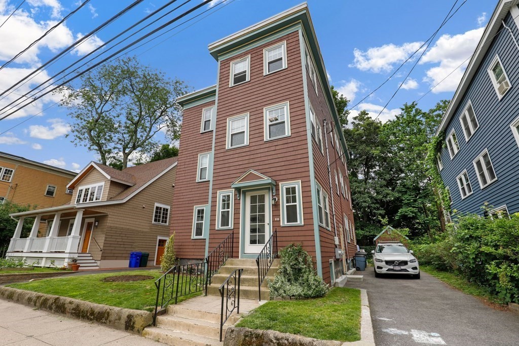 71-73 Brookley Road, Unit 1 Boston, MA 02130 - Photo 26 of 28 a front view of a house with a yard and potted plants