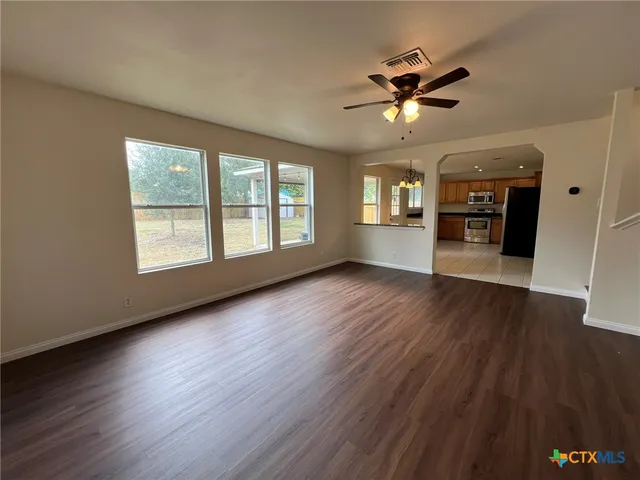 a view of an empty room with a window and wooden floor