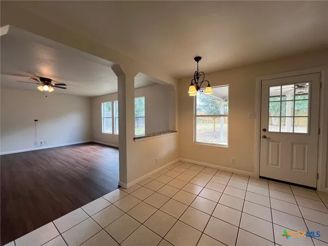 a view of an empty room with window and wooden floor