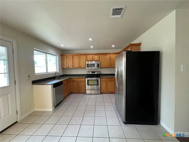 a kitchen with stainless steel appliances granite countertop a refrigerator and a sink