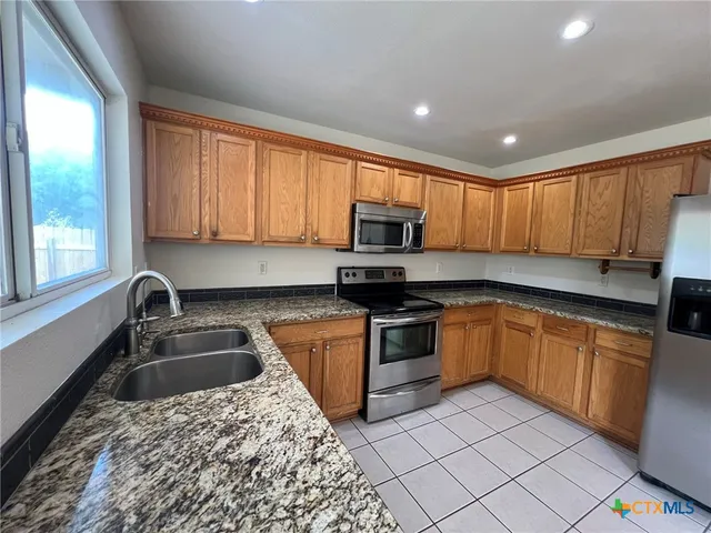 a kitchen with stainless steel appliances granite countertop a sink stove and cabinets