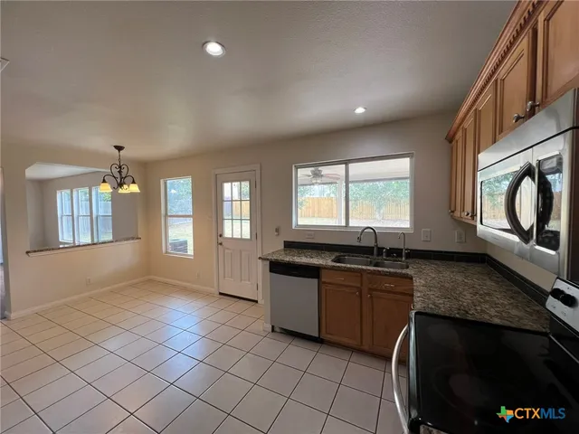 a kitchen with stainless steel appliances granite countertop a stove a sink and a microwave