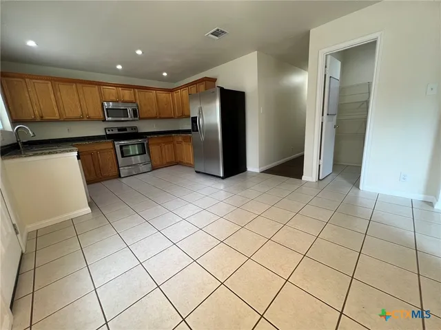 a kitchen with stainless steel appliances granite countertop a refrigerator and a sink