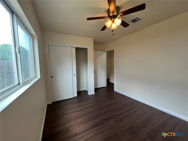 a view of an empty room with window and wooden floor