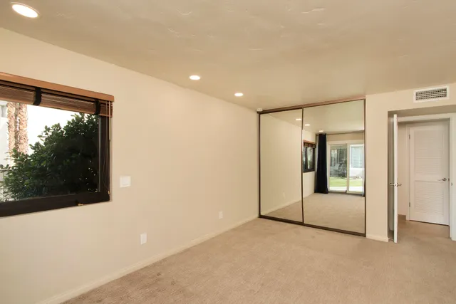 a view of an empty room with glass door and windows