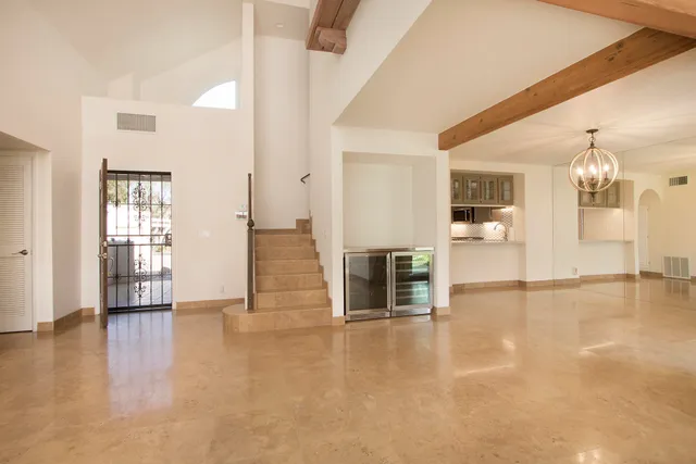 an empty room with wooden floor and a kitchen
