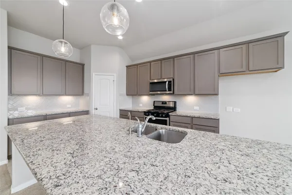 a kitchen with granite countertop a stove a sink and a refrigerator