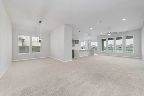 a view of an empty room with kitchen and window