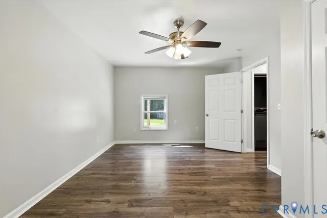 an empty room with wooden floor chandelier fan and windows