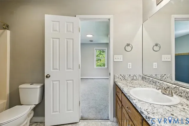 a bathroom with a granite countertop sink a toilet a mirror and shower