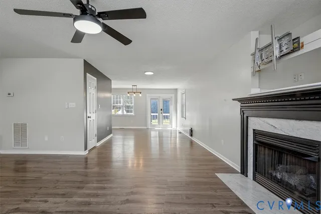 a view of an empty room with wooden floor fireplace and a window