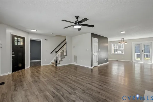 a view of an empty room with wooden floor and a ceiling fan
