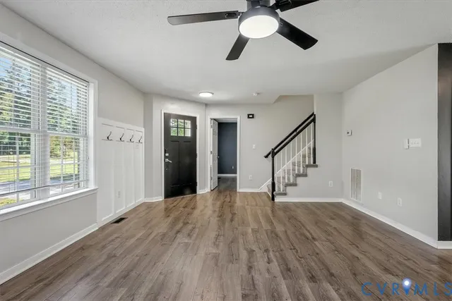 a view of empty room with wooden floor and fan
