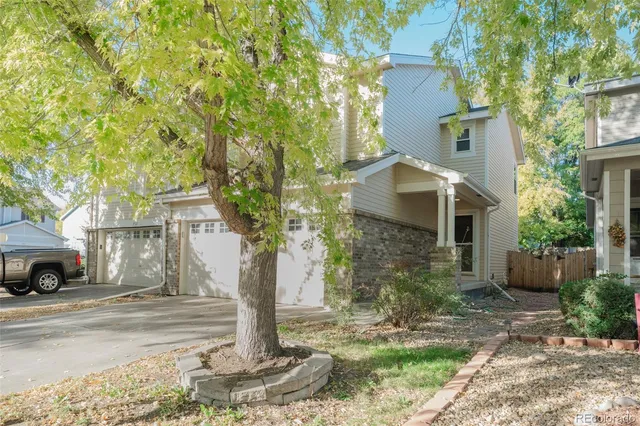 a front view of a house with a yard and large tree