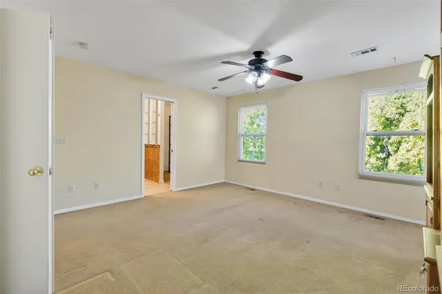 an empty room with windows and chandelier fan