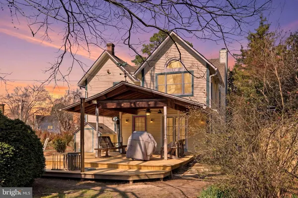 a view of wooden house with a yard and large trees