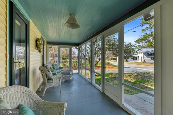 a view of a porch with chairs and floor to ceiling window
