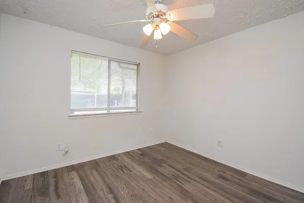 an empty room with a window and a fan