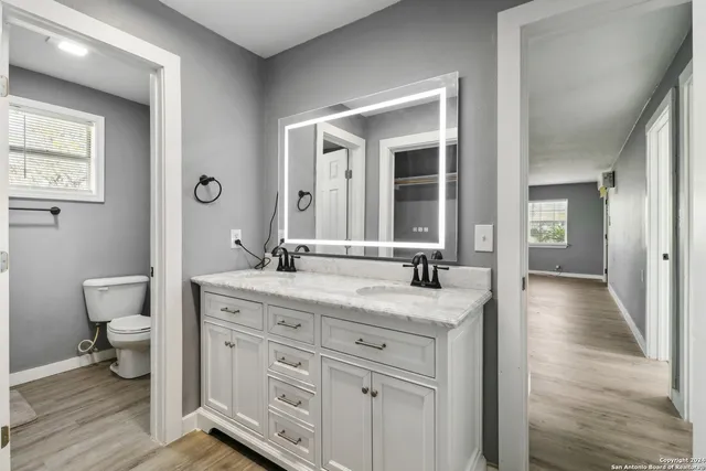 a bathroom with a granite countertop sink toilet and mirror