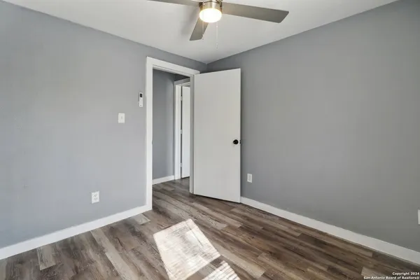 a view of a room with wooden floor and a ceiling fan