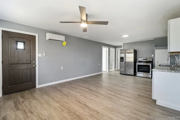 a view of a livingroom with wooden floor and kitchen space