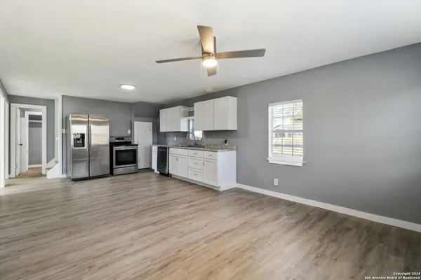 a view of a kitchen with a sink dishwasher cabinets and a large window
