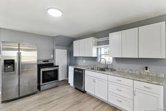 a kitchen with granite countertop white cabinets stainless steel appliances and sink