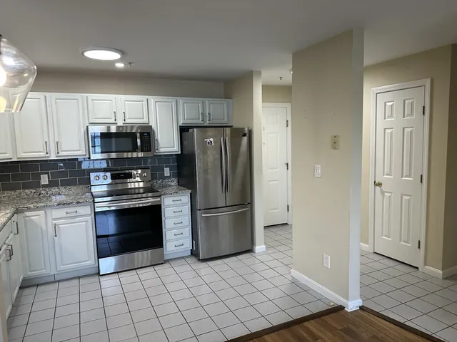 a kitchen with granite countertop a refrigerator and a stove top oven