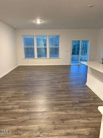 a view of an empty room with wooden floor and windows