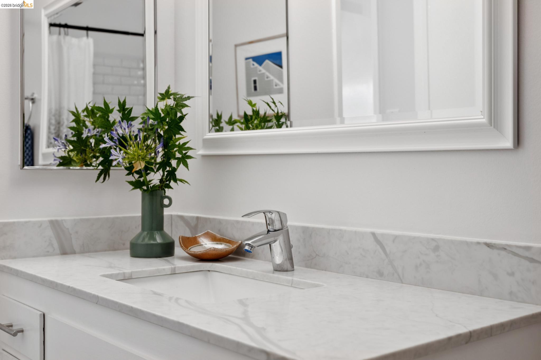 1340 Henry Street Berkeley, CA 94709 - Photo 44 of 52 Bathroom vanity featuring an integrated sink, polished chrome faucet, white cabinetry with silver hardware, and a framed mirror