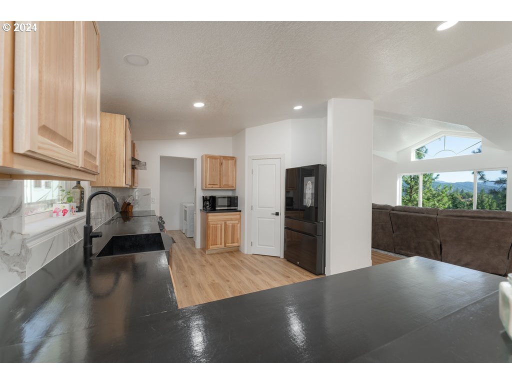 1069 Spring Brook Road Myrtle Creek, OR 97457 - Photo 14 of 43 a kitchen with stainless steel appliances kitchen island granite countertop a refrigerator a stove and a sink