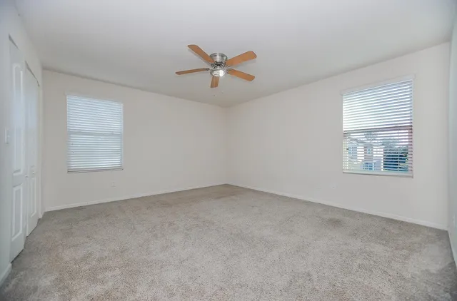 an empty room with windows and fan