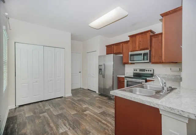 a kitchen with stainless steel appliances granite countertop a refrigerator a stove a sink and a white cabinets