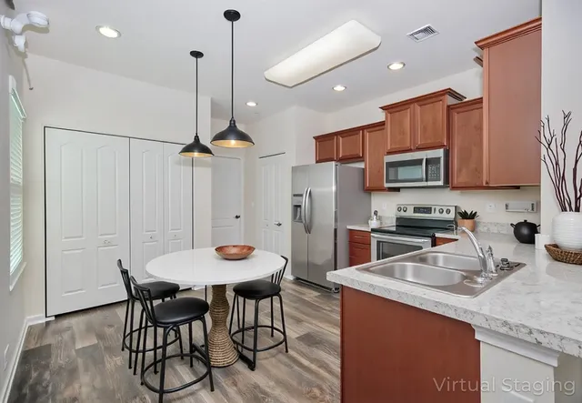 a kitchen with stainless steel appliances granite countertop a sink a stove a refrigerator and island with wooden floor