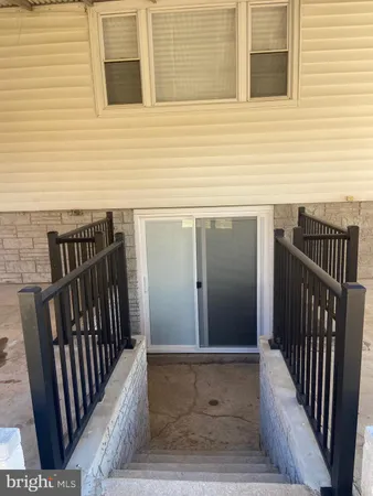 an empty room with wooden floor and a kitchen