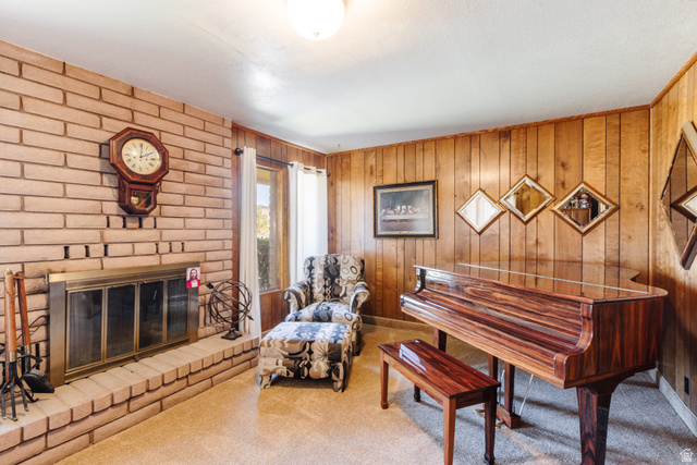 1470 Redwood Tree Street St. George, UT 84790 - Photo 26 of 53 Brick fireplace with a brass fire screen and hearth, wood-paneled wall, textured carpeting, and a window with white drapes
