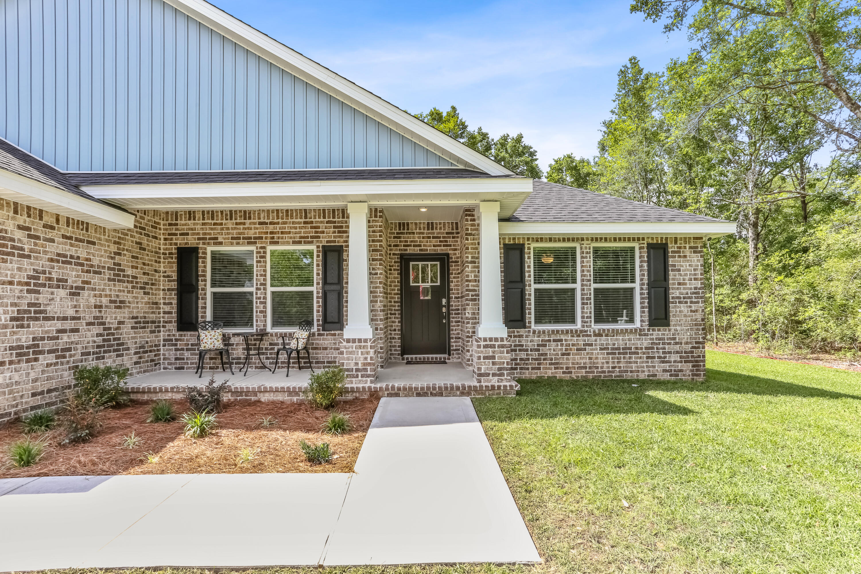 7568 Hatteras Drive Navarre, FL 32566 - Photo 2 of 44 a front view of a house with a garden and patio