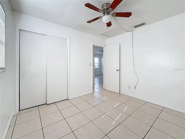 an empty room with closet and a chandelier fan