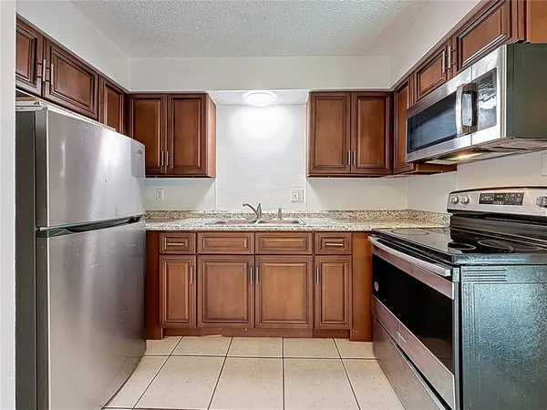 a kitchen with granite countertop a refrigerator and a stove top oven