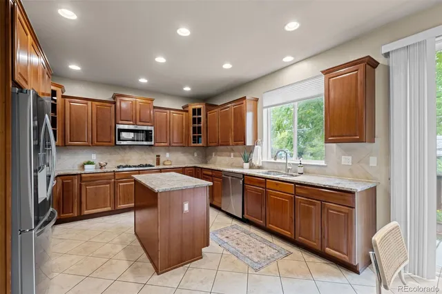 a kitchen with kitchen island granite countertop wooden cabinets stainless steel appliances a sink and a window