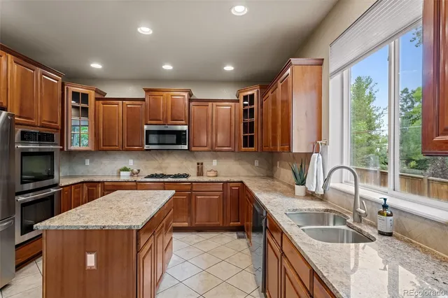 a kitchen with granite countertop kitchen island stainless steel appliances a sink and a window