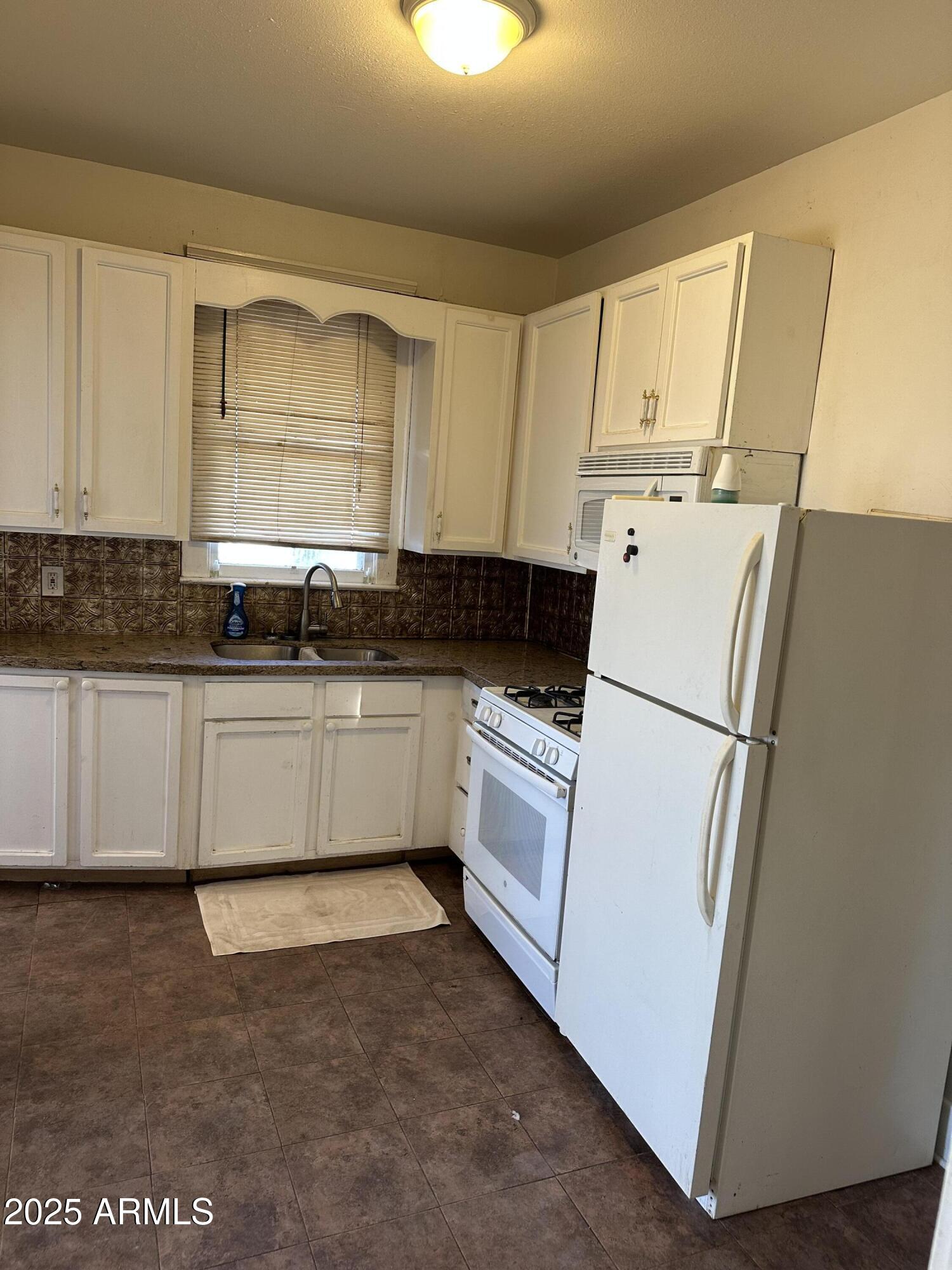 1008 North 27th Street Phoenix, AZ 85008 - Photo 5 of 15 a kitchen with a sink a refrigerator and cabinets