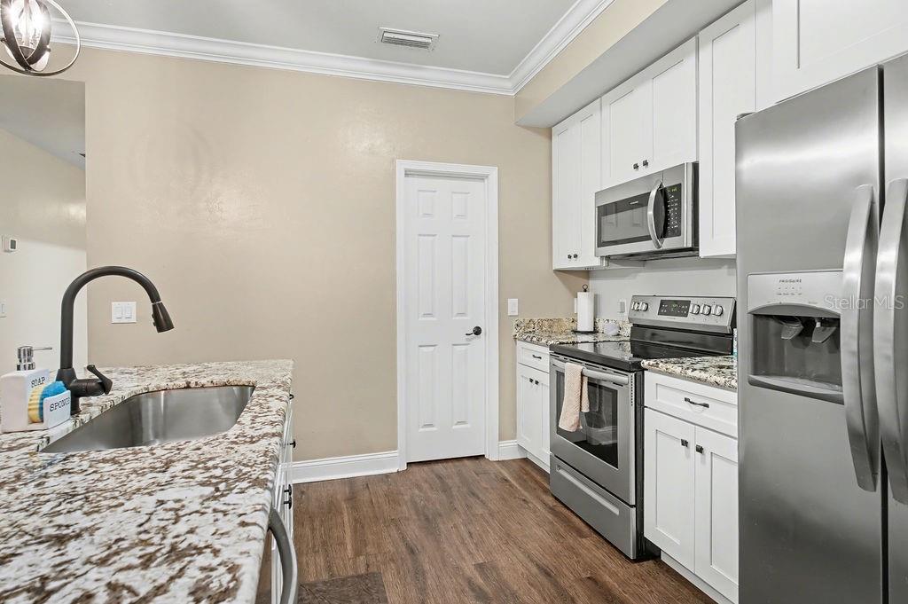 8291 Northeast 118th Terrace Bronson, FL 32621 - Photo 11 of 25 a kitchen with stainless steel appliances granite countertop a refrigerator a stove a sink and white cabinets with wooden floor