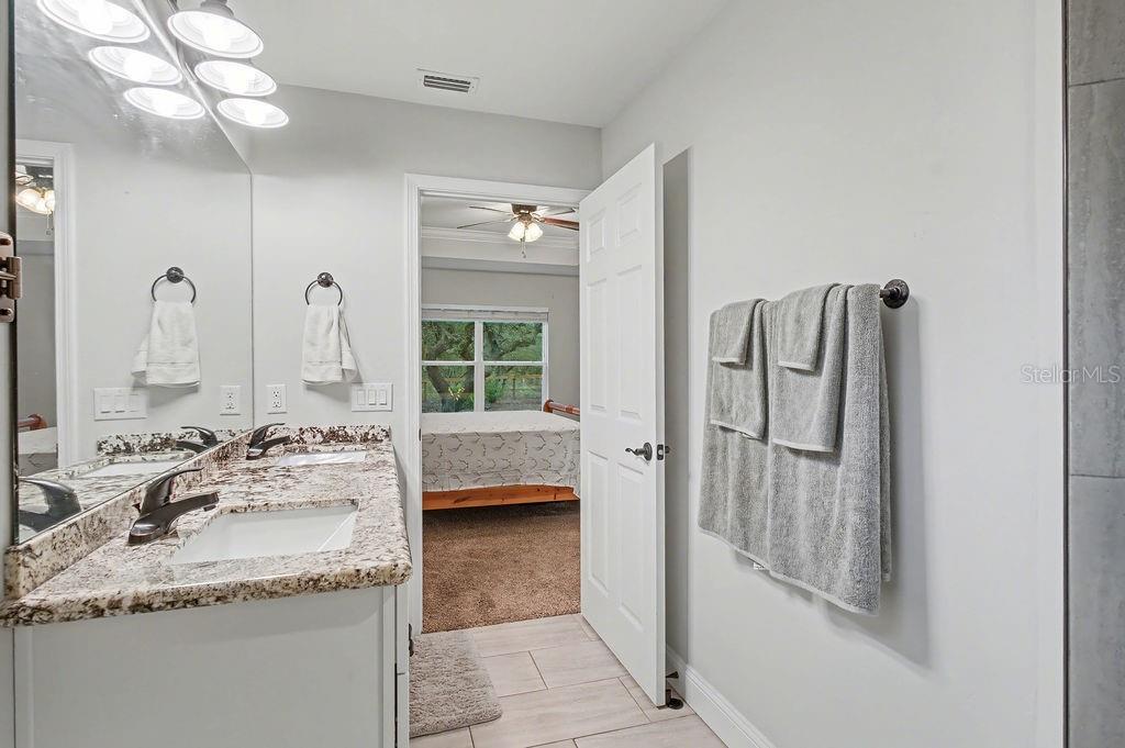8291 Northeast 118th Terrace Bronson, FL 32621 - Photo 21 of 25 a bathroom with a granite countertop sink and a mirror