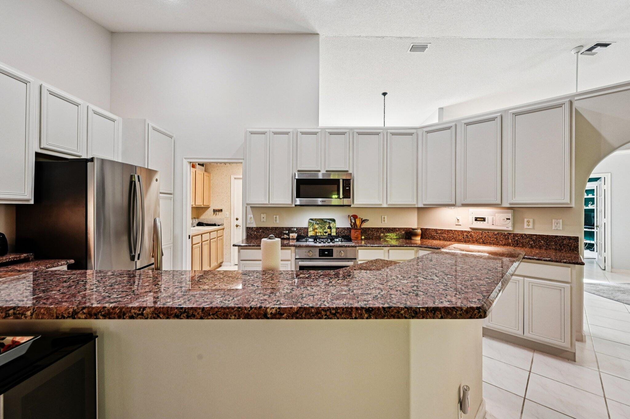 231 Sparrow Point Jupiter, FL 33458 - Photo 13 of 65 a kitchen with granite countertop a sink stove and refrigerator