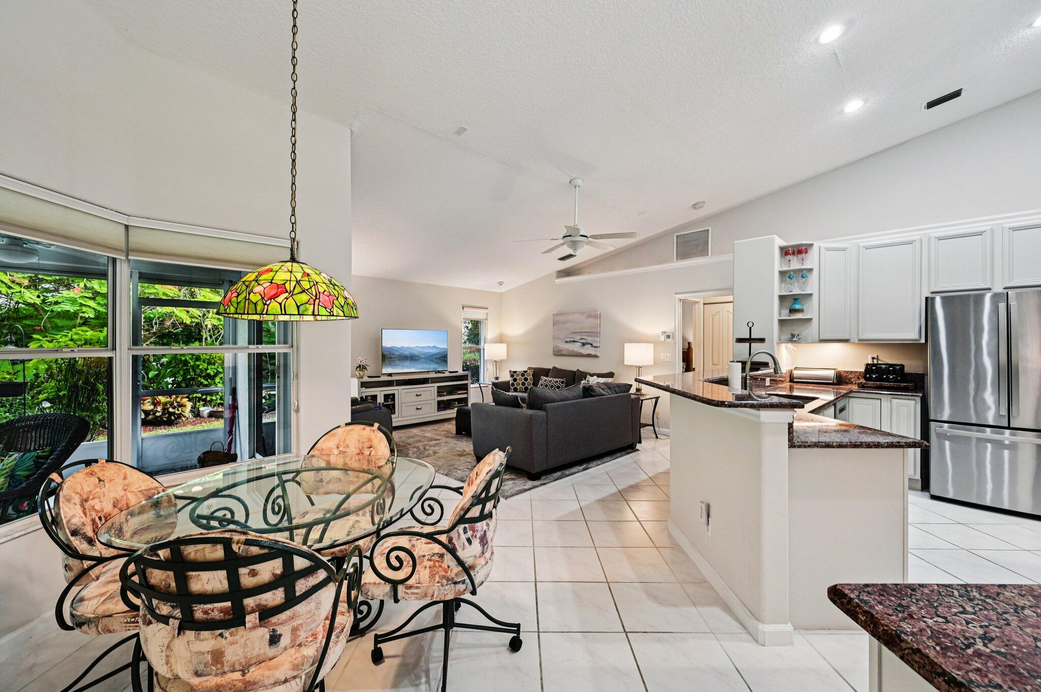 231 Sparrow Point Jupiter, FL 33458 - Photo 10 of 65 a kitchen with stainless steel appliances kitchen island granite countertop a table and chairs in it