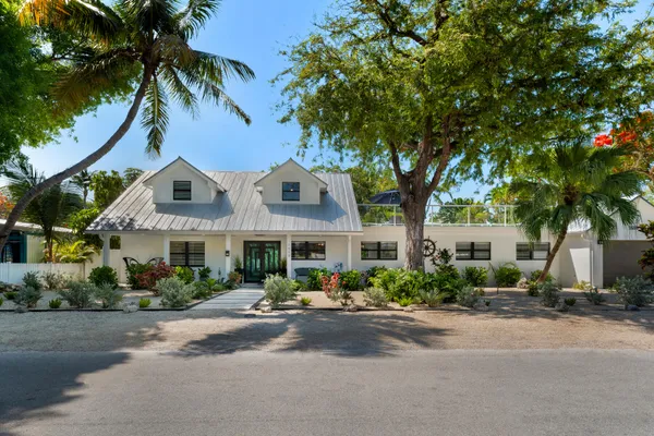 a front view of a house with a yard and potted plants